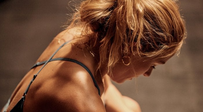 A close up of a young woman mid-exercise, looking down at the floor.