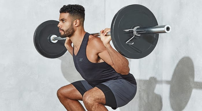 man squatting with barbell